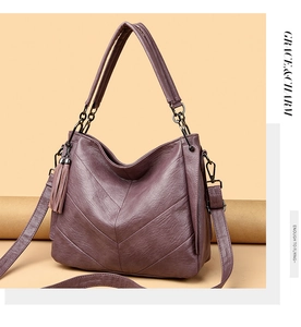 Detail of purple soft leather handbag with V-shaped stitching and tassel accent