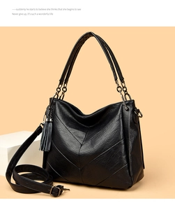 Detail of black tote bag with chevron stitching, dual handles and leather tassel charm