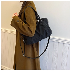 Side view of large black matte tote bag with shoulder strap worn over a wool coat