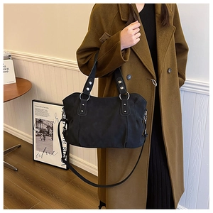 Close-up of large matte black tote bag with silver rivets and metal ring accents