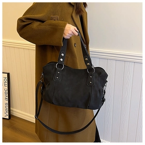 Detail of matte black tote bag with silver rivets and detachable shoulder strap on a model