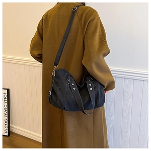 Detail view of a large black matte tote bag with silver studs on a stylish shoulder strap