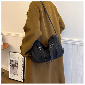 Detail of a large black vintage hobo bag with silver rivets shown on a shoulder