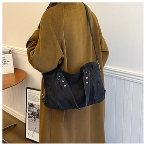 Detail of black high-capacity tote bag with silver rivets and long shoulder strap