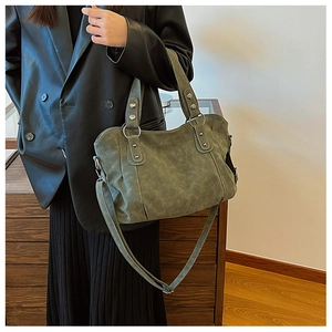 Detail of dark green suede tote bag with silver rivets and elegant round handle