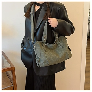 Detail of vintage olive green suede tote bag with metal buckles and rivets