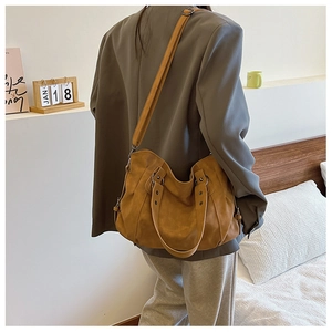 Retro brown oversized tote bag with adjustable shoulder strap worn with a grey suit