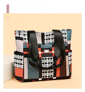 Dettaglio della borsa tote color-block con logo in metallo e tasche laterali in tessuto