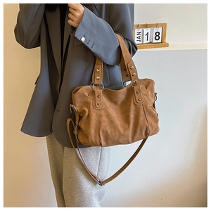 Detail of vintage brown matte leather tote bag with metal rings and studs on a model