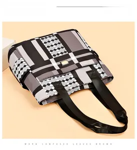 Dettaglio della borsa tote geometrica con logo dorato e ampia tracolla nera
