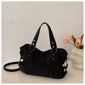 Detail of black suede tote bag with metal rings and rivets in a modern interior setting