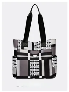 Dettaglio della borsa tote geometrica con manici in nylon nero e tasca laterale