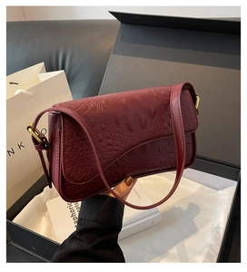 Vue détaillée du sac à bandoulière bordeaux motif crocodile avec boucles dorées