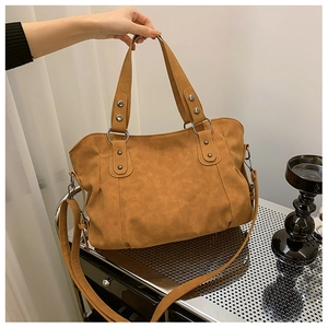 Detail of vintage brown tote bag showing matte faux leather texture and metallic rivets