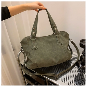 Close-up of matte grey-green tote bag with silver metal ring and rivet decorations