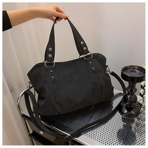 Detail of black matte shoulder bag showing silver ring hardware and adjustable strap