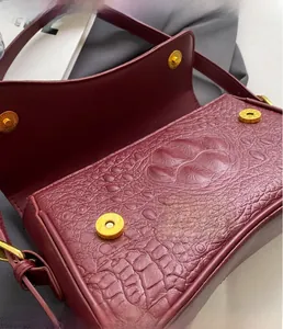 Détail du sac bordeaux motif crocodile avec fermoirs magnétiques dorés de luxe