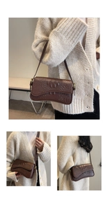 Détails de la texture crocodile marron foncé et boucle dorée sur un sac à bandoulière