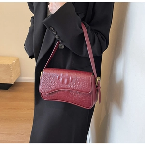 Sac sous le bras rétro français en cuir croco bordeaux porté avec un blazer noir chic