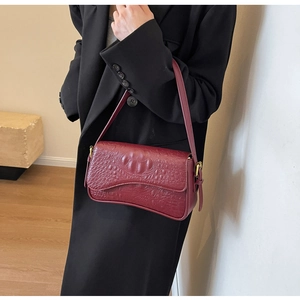 Détail du sac à bandoulière bordeaux motif crocodile avec boucle en métal doré vintage