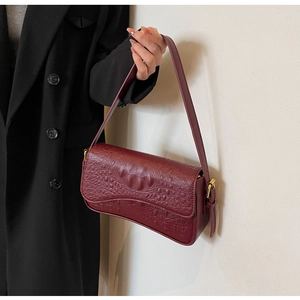 Gros plan du sac baguette bordeaux à motif crocodile avec boucle dorée en métal