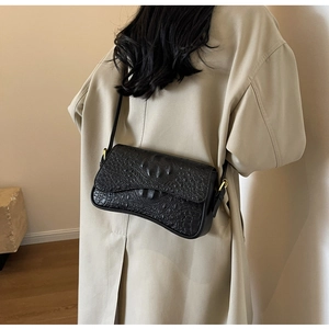 Détail du sac sous le bras en cuir à motif crocodile noir avec boucle dorée
