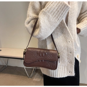Détail du sac baguette marron vintage avec gaufrage crocodile et boucle dorée