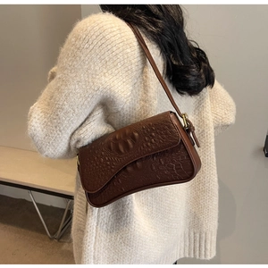 Sac à bandoulière marron motif crocodile sur mannequin portant un pull beige chic