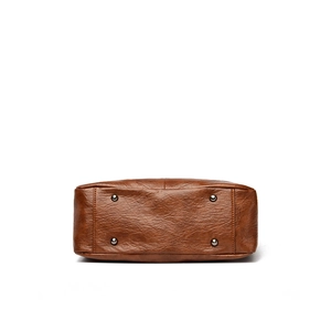Bottom view of brown leather tote bag with protective metal feet and lychee texture