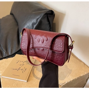 Détail du sac sous le bras bordeaux à motif crocodile avec boucle en métal doré ajustable