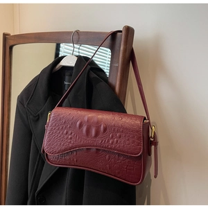 Détail du sac à bandoulière en cuir gaufré crocodile bordeaux avec boucle dorée
