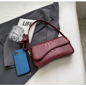 Gros plan détaillé du cuir à motif crocodile rouge foncé avec boucle dorée