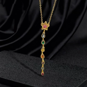 Collana a stella dorata con gemme arcobaleno a goccia su sfondo di seta nera lussuosa