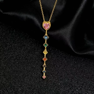 Dettaglio collana dorata con pietra a cuore rosa e sette gemme quadrate multicolore