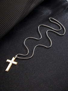 Vue macro d'un pendentif croix dorée avec chaîne argentée sur fond noir texturé