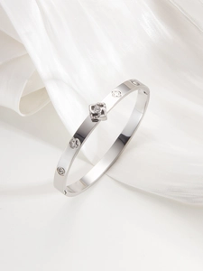 Detail of silver clover bangle with rhinestones on white silk background