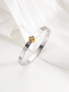 Macro view of silver titanium steel bangle with gold rhinestone square and clover patterns