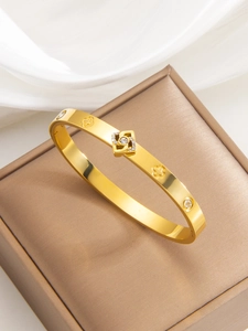 Detail of 18k gold plated clover bangle with sparkling crystals on silk background