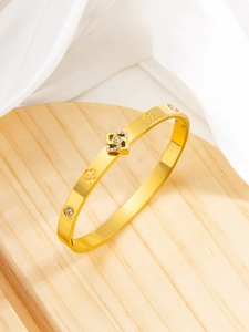 Detail of 18k gold plated bangle with hollow clover and crystal spinning square charm