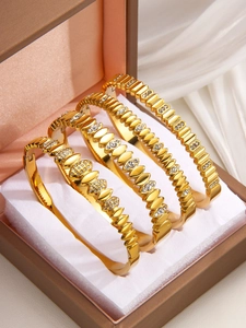 Detail of four gold-tone stainless steel bracelets with rhinestones in a luxury jewelry box