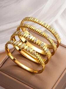 Detail of four-piece gold-plated bracelet set with wave texture and crystal studs