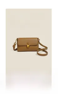 Macro detail of brown leather texture with white stitching and gold metal clasp on a bag