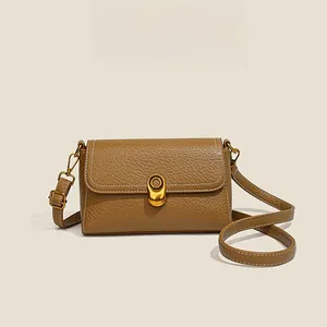 Detailed close-up of brown litchi grain leather bag with gold clasp and white stitching