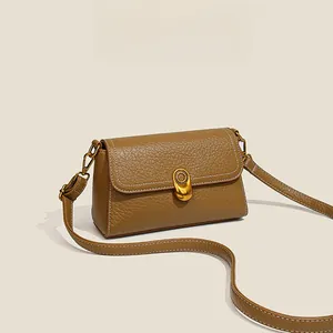 Detail of brown lychee texture leather bag with gold buckle and white stitching