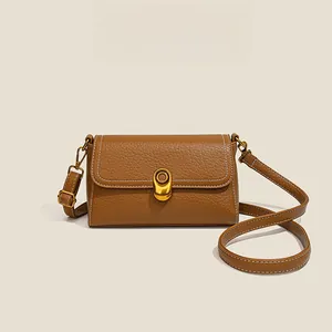 Detail of lychee pattern leather square bag with gold metal buckle and white stitching