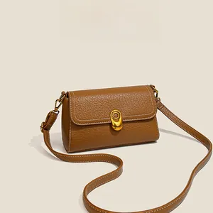 Detail of brown litchi pattern leather bag with gold buckle and white stitching