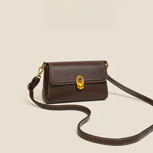 Detail of brown leather chain bag showing lychee texture and white stitching with gold lock