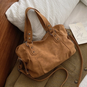 Retro camel suede tote bag with silver rivets and dual straps shown in a cozy home setting