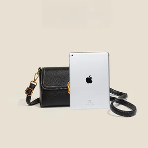 Black pebbled leather crossbody bag compared with iPad to showcase mini size and dimensions