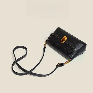 Detail of black pebbled leather handbag with contrast stitching and golden oval lock